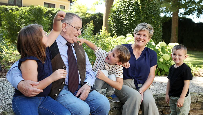 Eine ältere Frau und ein älterer Mann sitzen zwischen zwei Buben und einem Mädchen.