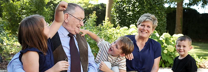 Eine ältere Frau und ein älterer Mann sitzen zwischen zwei Buben und einem Mädchen.